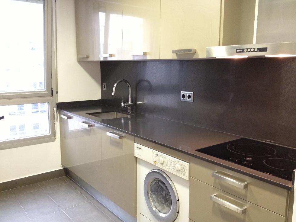 Cocina en París, Francia, con muebles en acabado seda color champán, diseño minimalista y encimera técnica junto al Arco del Triunfo.