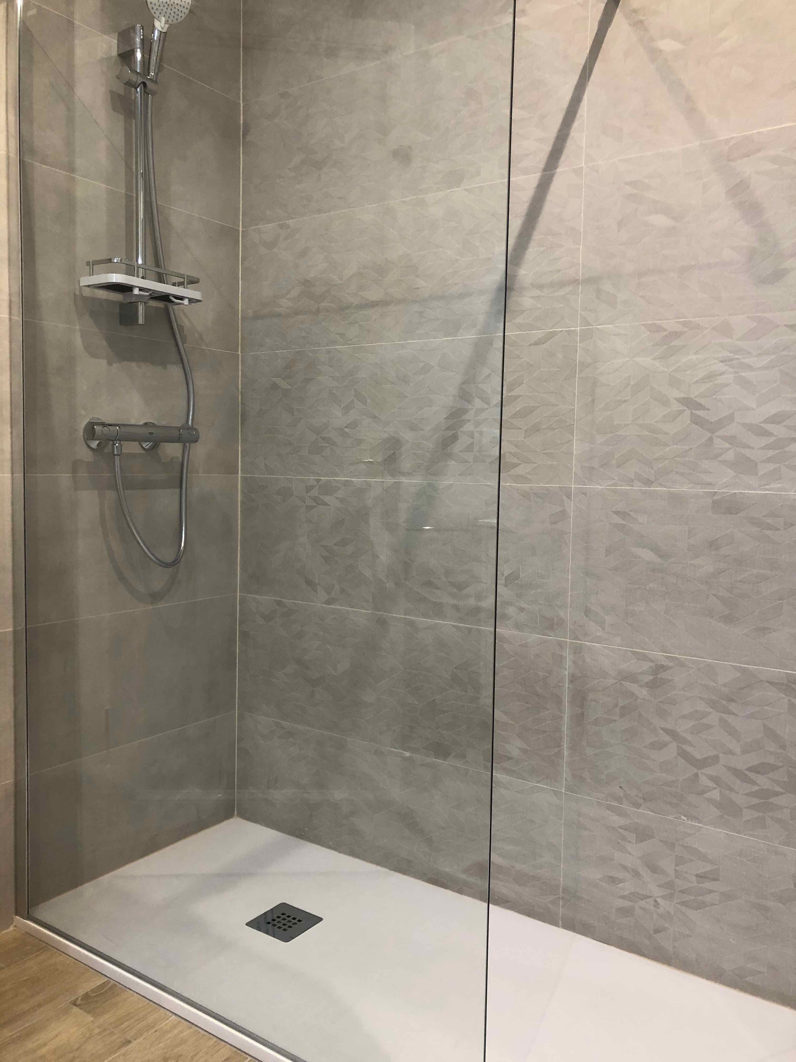 Plato de ducha pizarra blanco con mampara fija y suelo imitación madera. Reforma integral de vivienda en Carrer Sicilia. Eixample. Barcelona