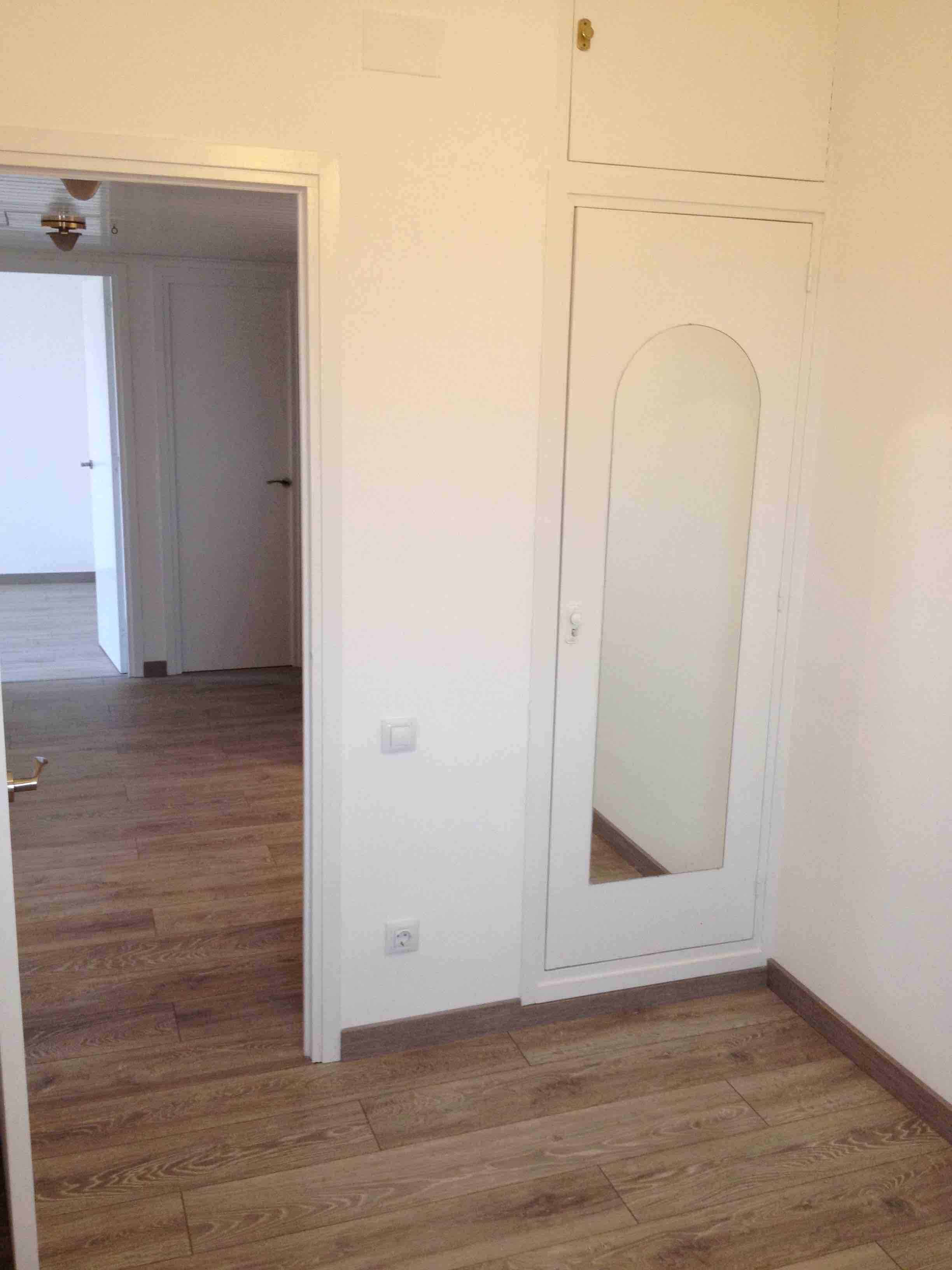 Detalle de la zona del recibidor con suelo laminado y armario recuperado y lacado en blanco. Reforma integral piso Josep Pla. Sant Marti. Barcelona