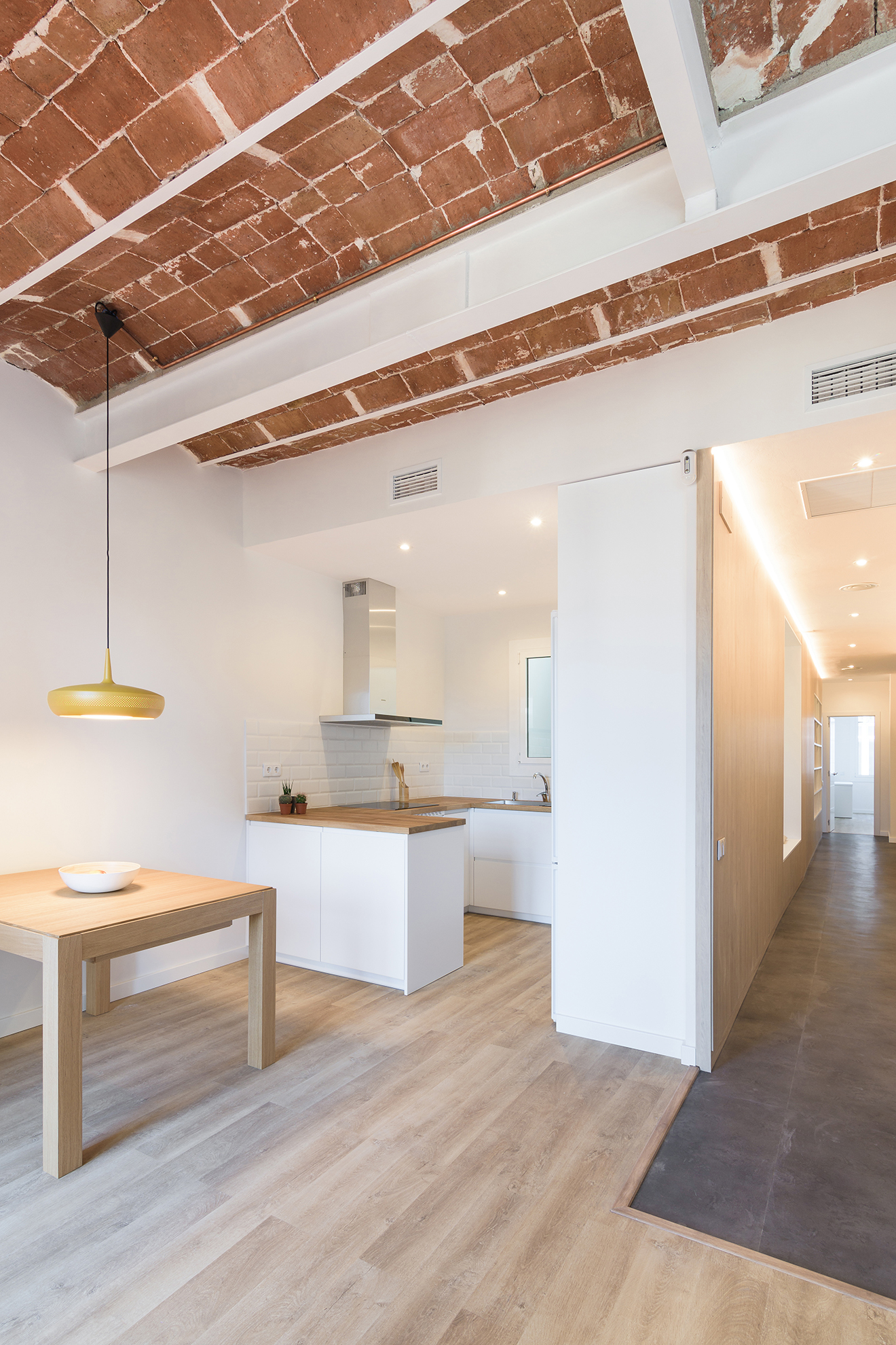 Detalle de viga de hierro de refuerzo estructural en una cocina abierta con techo de bóveda catalana en el Eixample, Barcelona.