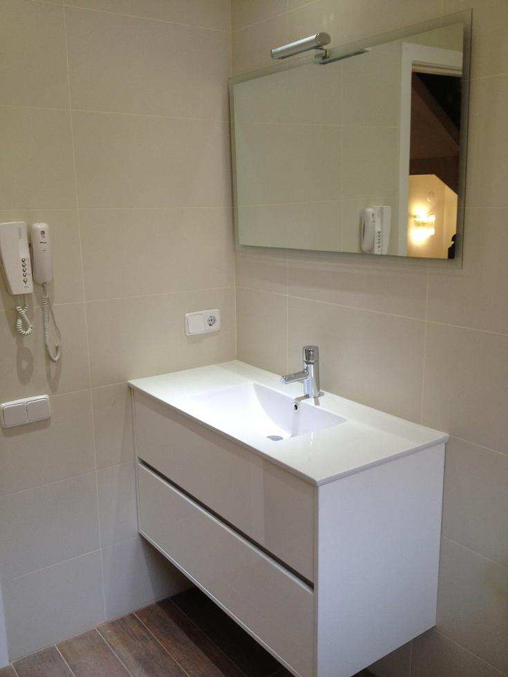Baño en Sant Sant Cugat con mueble de lavabo de 80 cm en blanco mate, cajones amplios y pavimento cerámico que imita listones de madera oscura en Barcelona.
