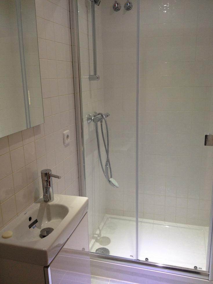 Aseo de cortesía en Sant Cugat con mueble de lavabo de fondo reducido y pequeño plato de ducha acrílico, diseño compacto y aprovechamiento máximo del espacio en una rehabilitación integral.