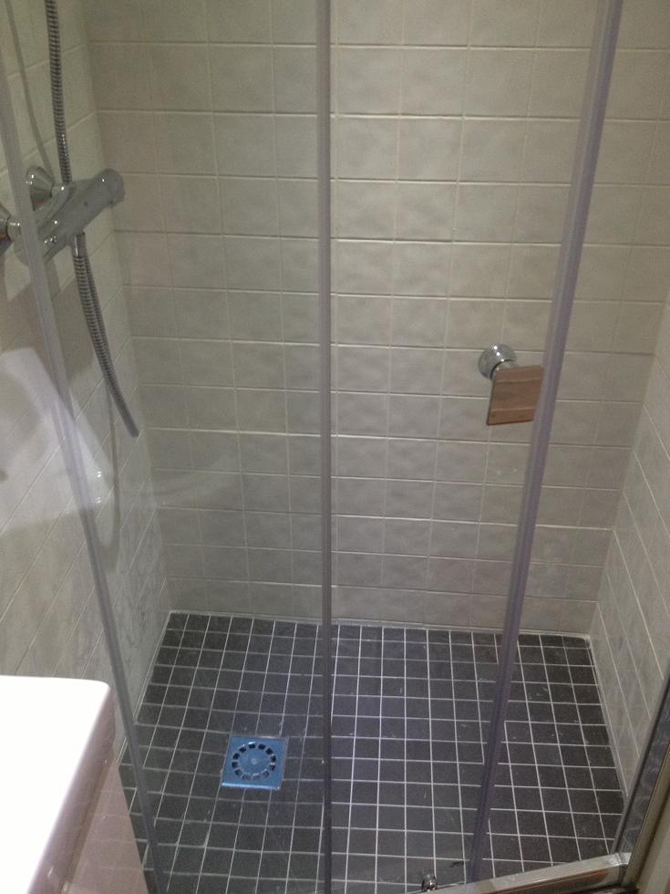 Baño auxiliar en Sant Cugat con una ducha de obra de dimensiones compactas, plato a ras de suelo y revestimiento cerámico coordinado tras una rehabilitación integral.