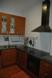 cocina con encimera negra y mobiliario madera. Eixample. Barcelona