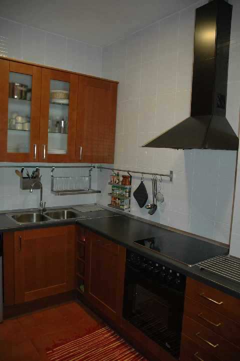 Cocina con encimera negra y mobiliario madera. Eixample. Barcelona