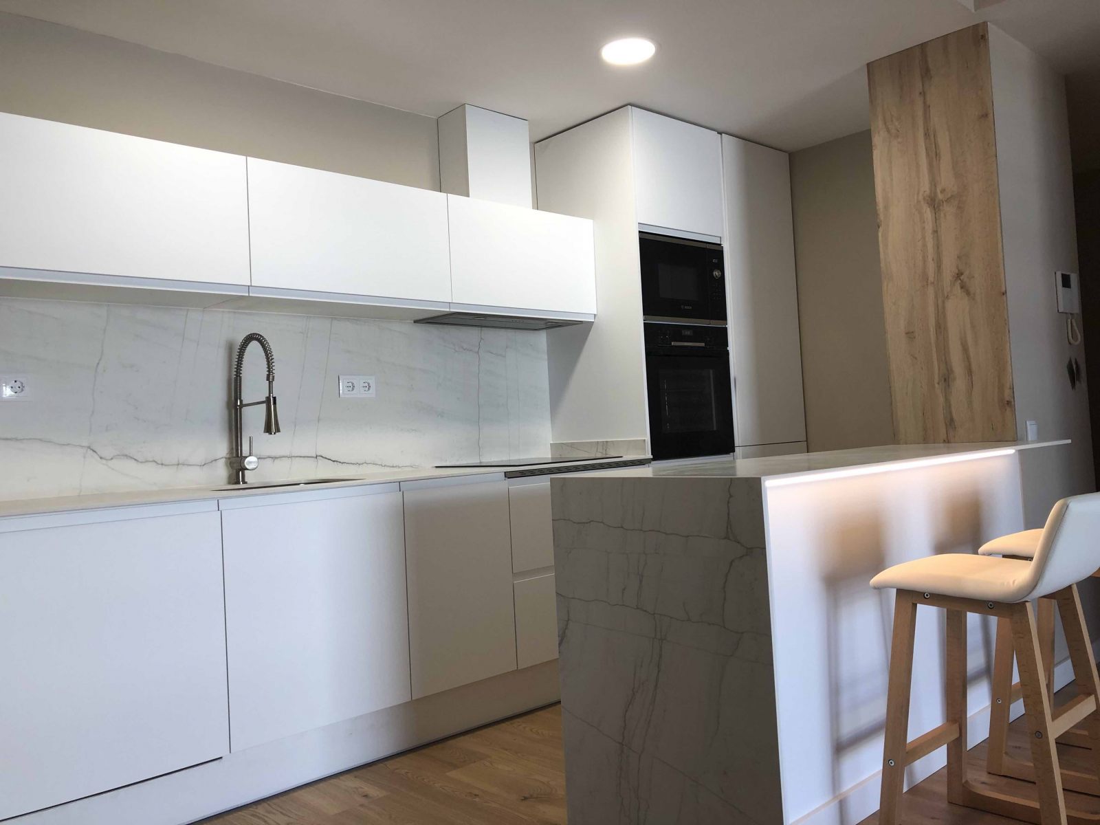 Cocina abierta a salón con Dekton y forrado de madera. Reforma Les Corts. Barcelona