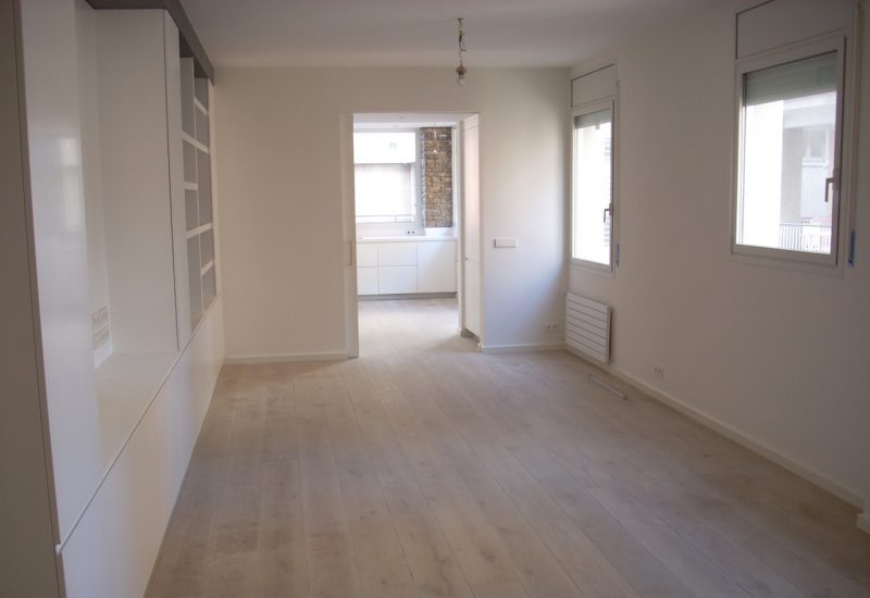 Salón comedor diáfano en Sarrià-Sant Gervasi con corredera oculta, suelo de tarima de madera natural, grandes ventanales y diseño de espacios abiertos para maximizar la luminosidad en Barcelona