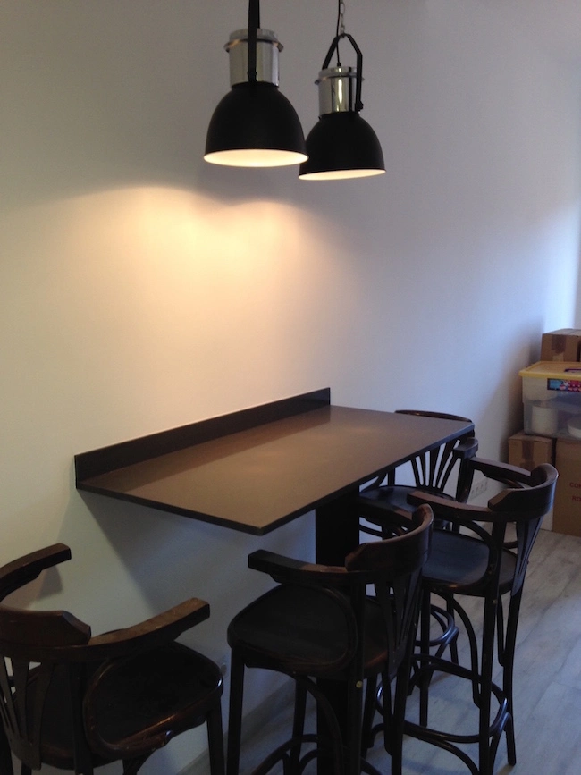 Pequeña barra de madera natural volada sobre pared blanca en una cocina de 50 metros cuadrados, diseñada para optimizar el espacio de comedor.