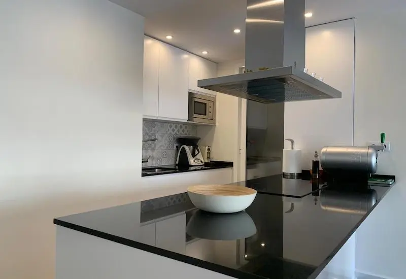 Reforma integral de cocina con isla central de granito negro en la calle Sepúlveda, barrio de Sant Antoni, Barcelona.